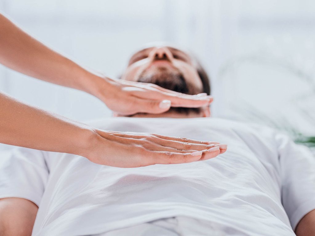 cropped shot of bearded man receiving reiki healing session above stomach